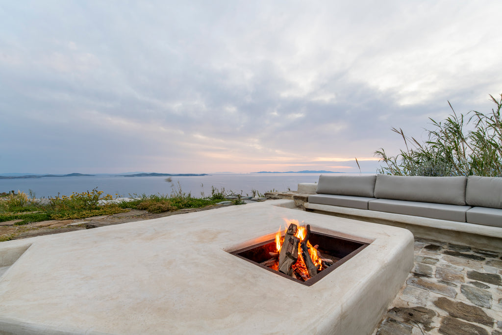 Outdoor fire pit with a scenic view of water and sky.