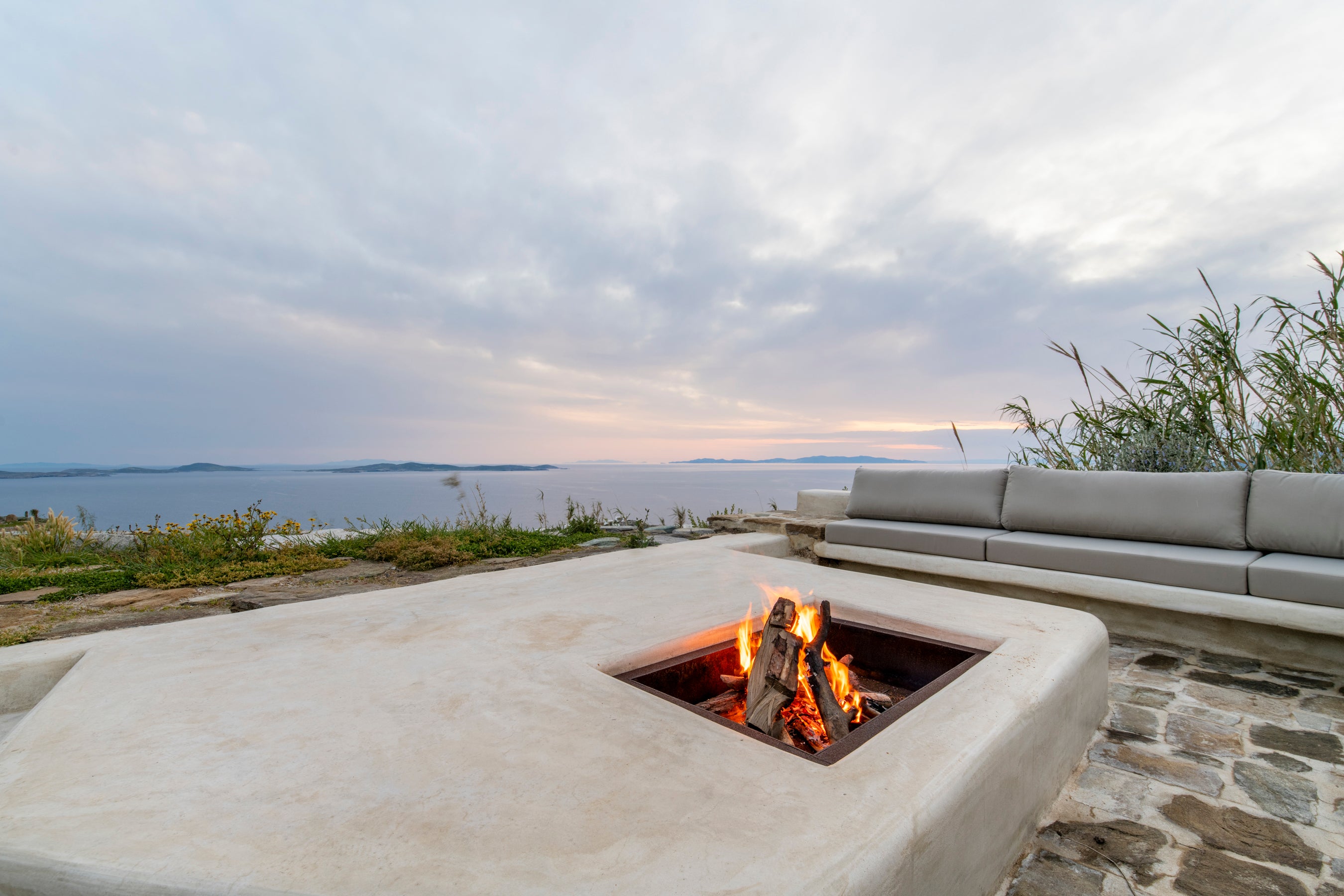 Outdoor fire pit with a scenic view of water and sky.