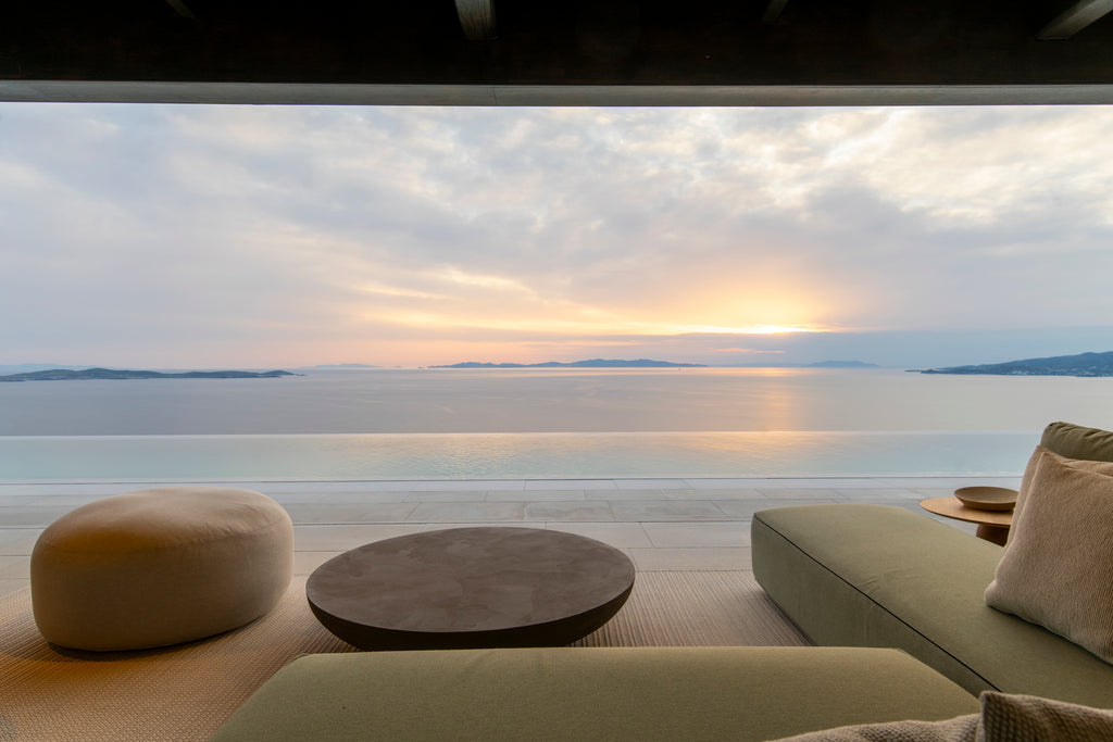 Modern outdoor furniture set with a scenic view of water and sky.