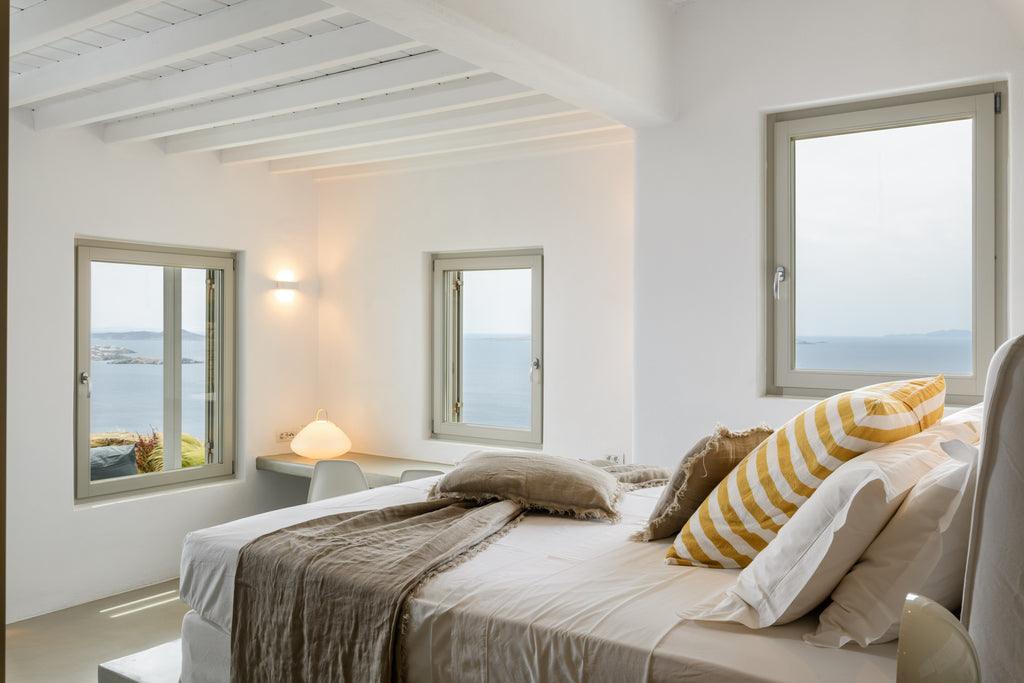 Modern bedroom with large windows offering a view of the sea.