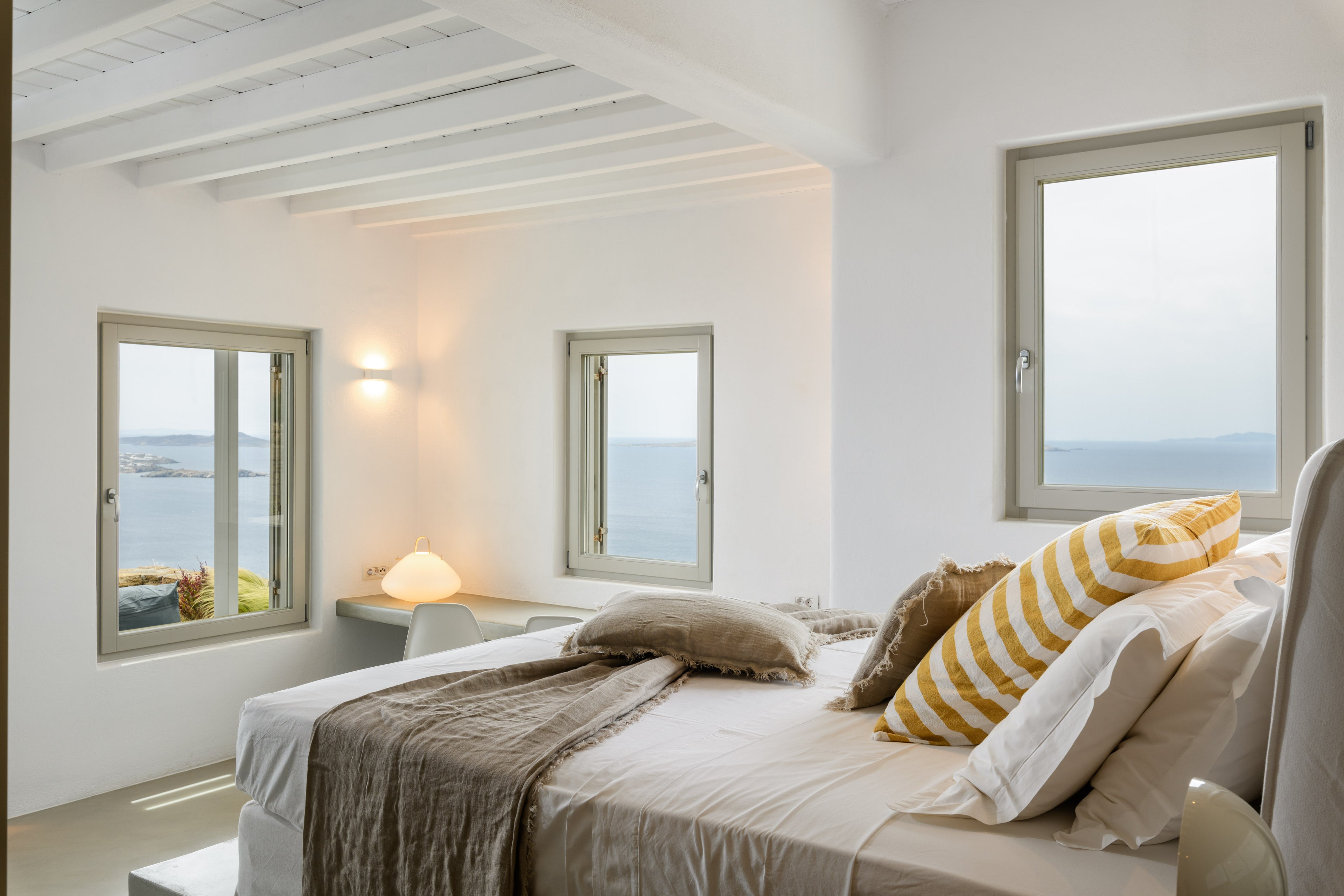 Modern bedroom with large windows offering a view of the sea.