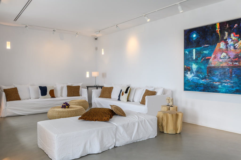 Modern living room with white sofas, brown cushions, and a colorful abstract painting on the wall.