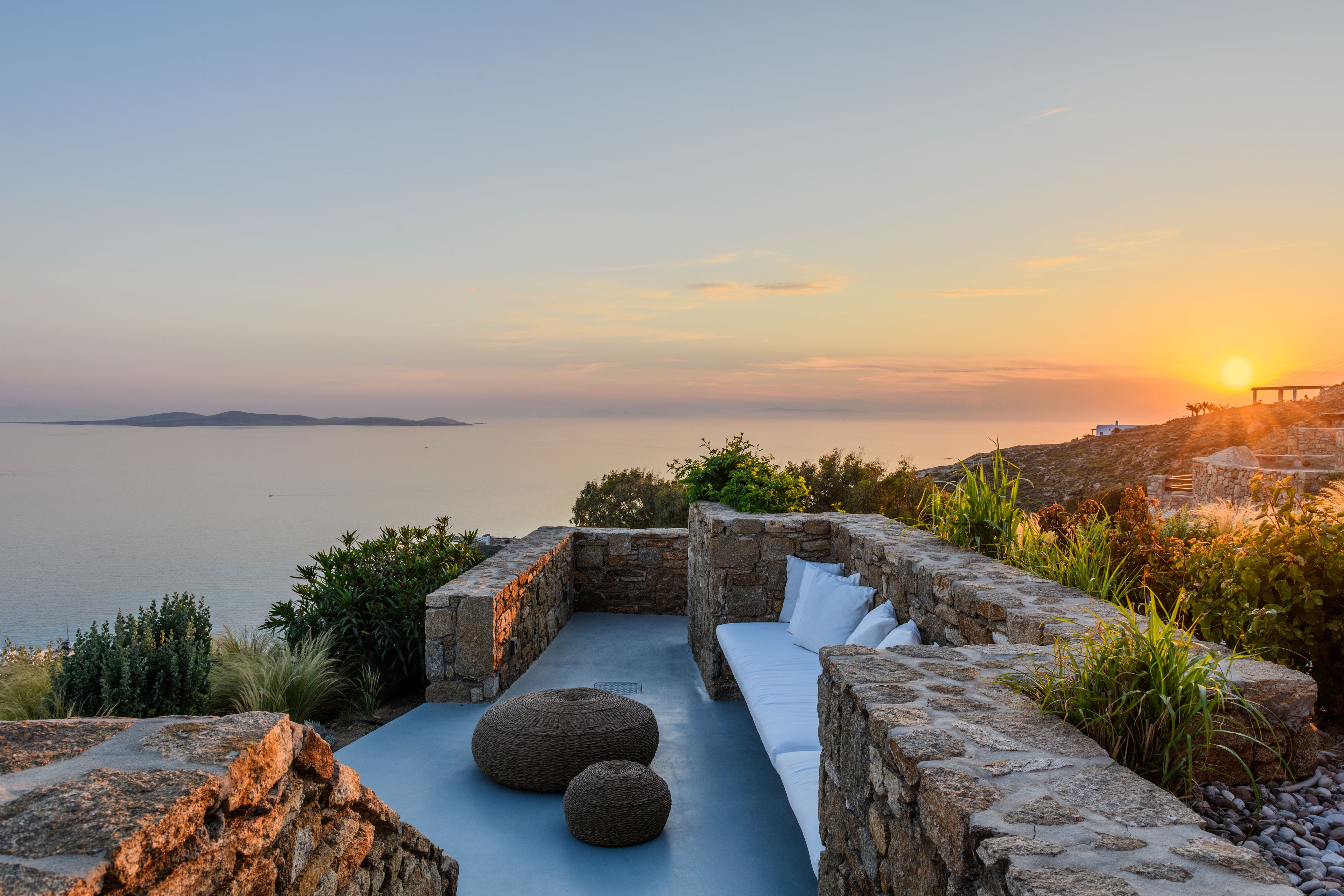 Outdoor seating area with a view of the ocean during sunset.