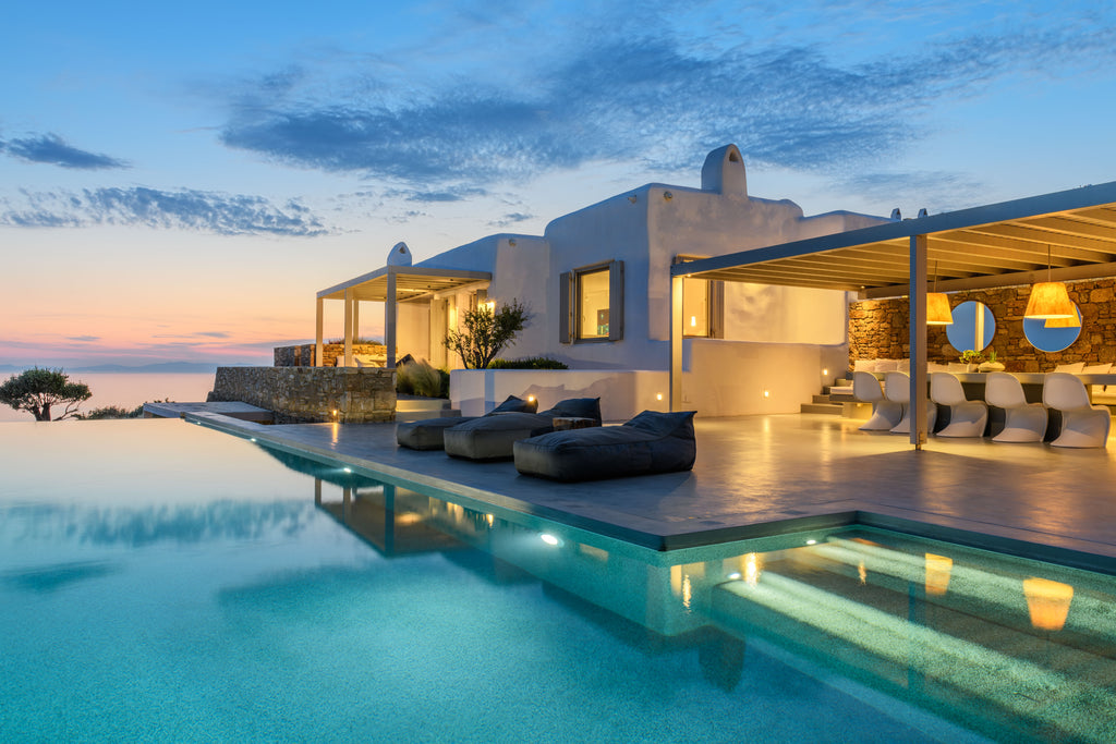 Luxury poolside area with a modern building and evening sky.