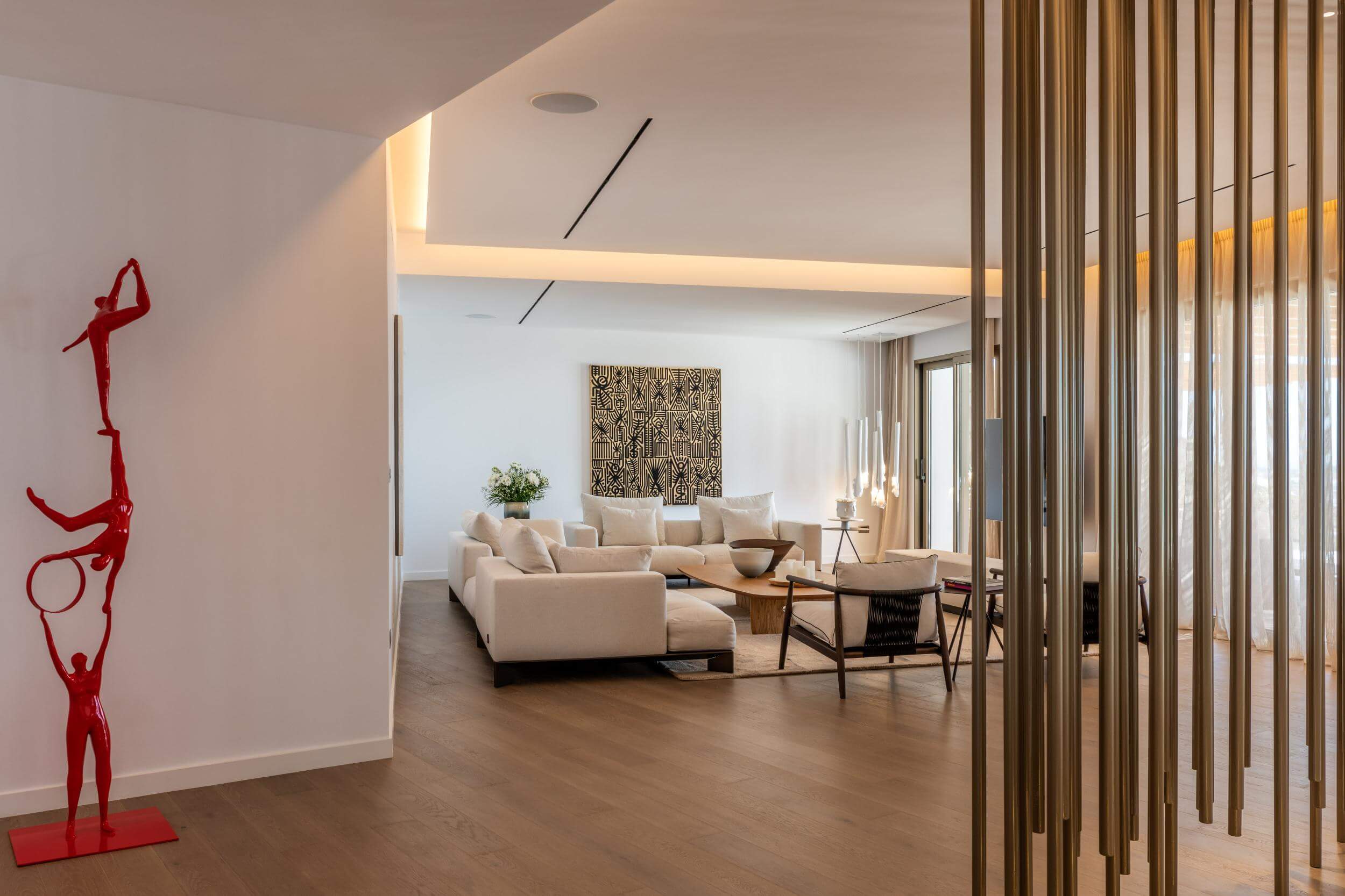 Modern living room with a red sculpture, beige sofas, and wooden floor.