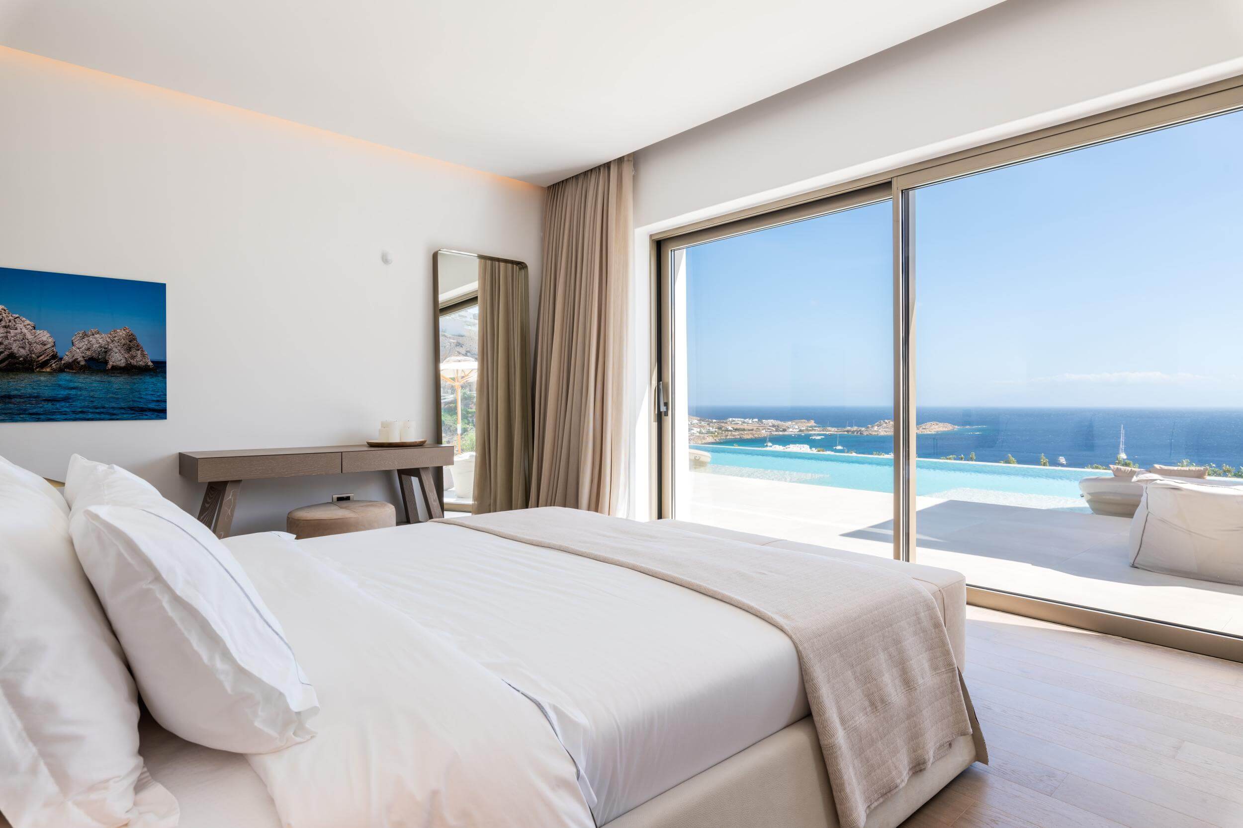 Modern bedroom with a large window offering a view of the ocean.