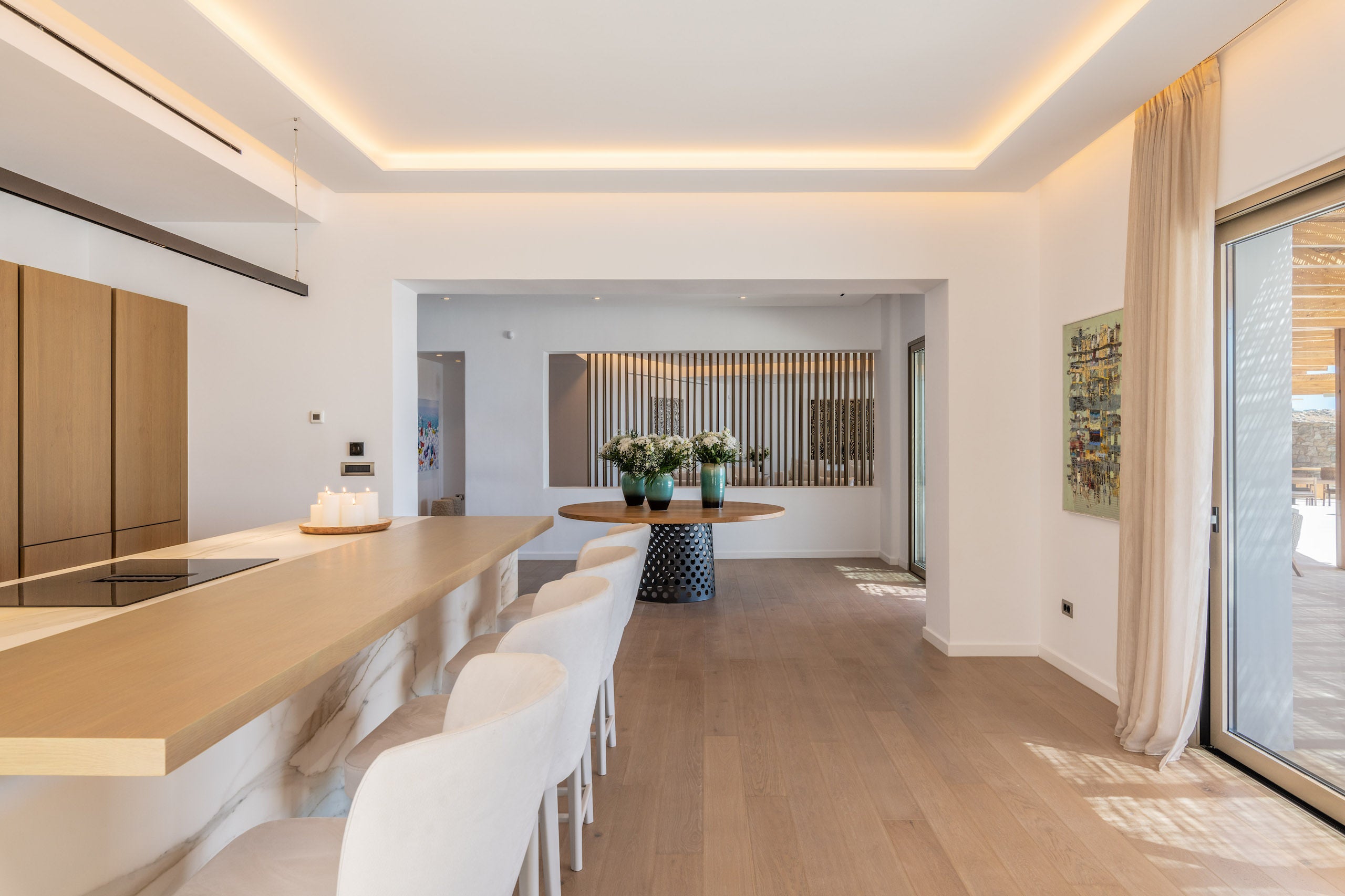 Modern kitchen with wooden dining table and white chairs, featuring a large window.